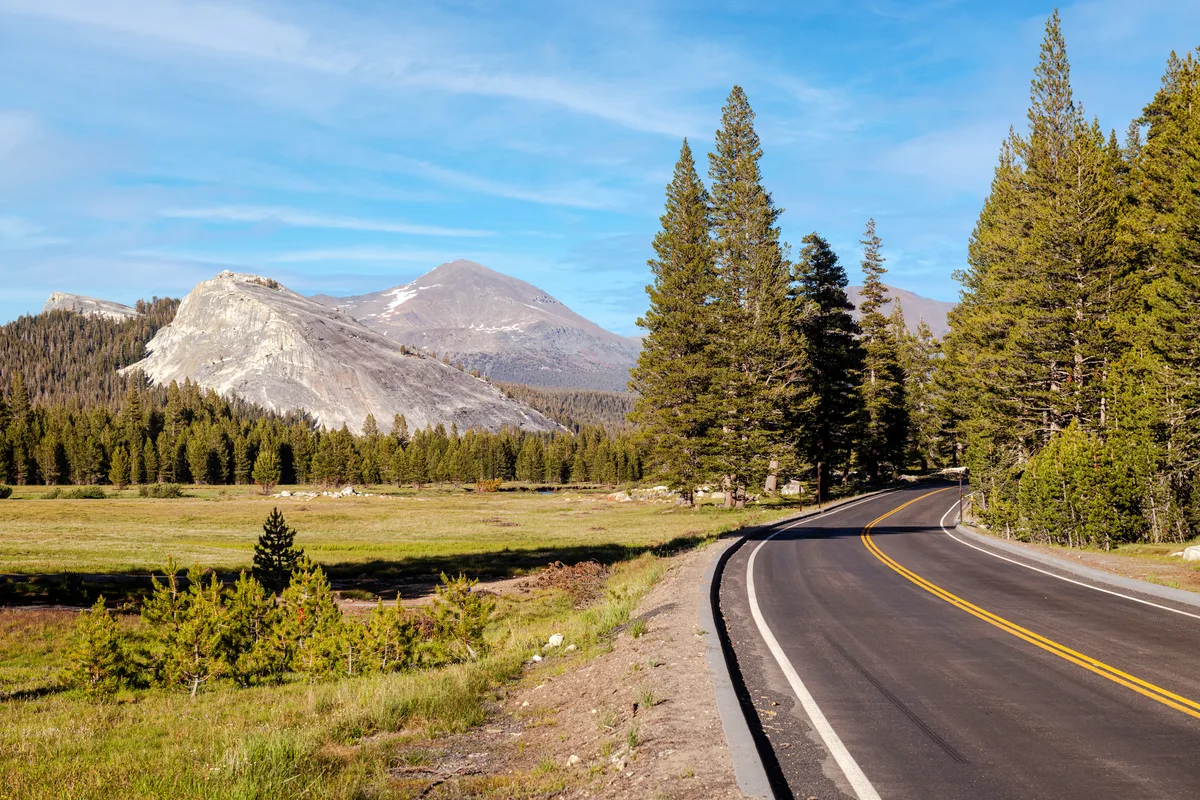 This breathtaking photograph showcases Tuolumne Meadows alongside the scenic Tioga Pass Road in Yosemite National Park. The expansive meadows, filled with vibrant wildflowers and lush grasses, create a stunning contrast against the towering granite peaks that define the landscape. Tioga Pass Road meanders through this picturesque setting, offering travelers a chance to experience the natural beauty of the Sierra Nevada. As one of the highest paved roads in California, it provides sweeping views of the surrounding wilderness, including sparkling alpine lakes and dramatic rock formations. In the summer, the meadows come alive with the sounds of nature, inviting visitors to explore its trails and take in the panoramic vistas. This enchanting scene captures the essence of the Sierra Nevada’s beauty, making Tuolumne Meadows and Tioga Pass Road a must-visit destination for those seeking adventure and tranquility in Yosemite National Park.